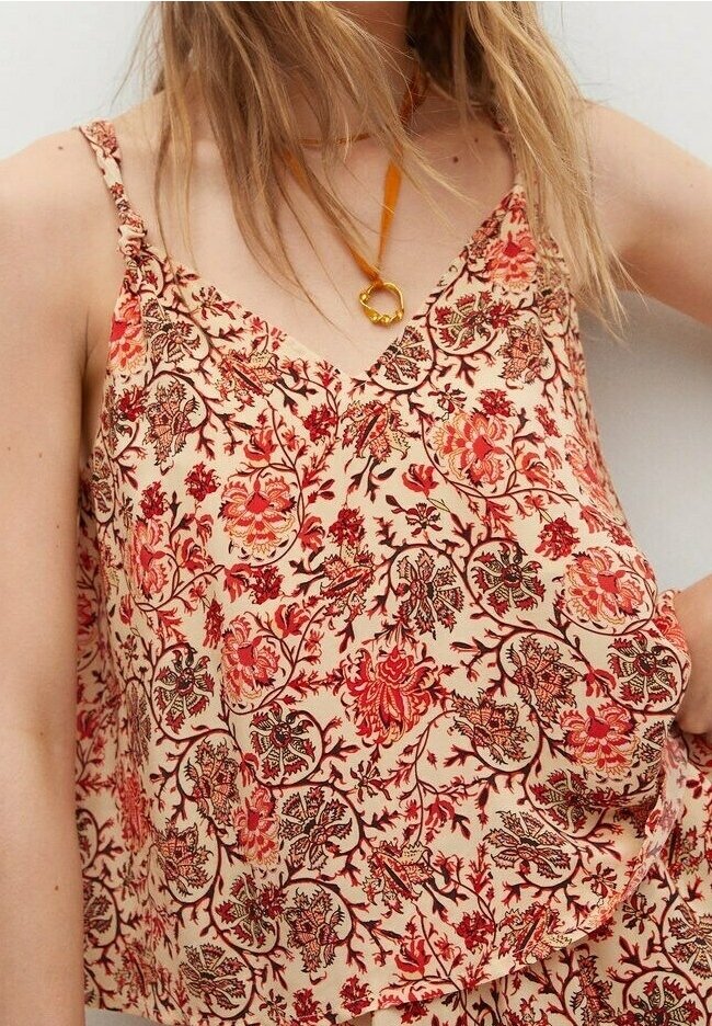 Débardeur à motifs floraux en crème avec des rouges et des bruns. Il se caractérise par des bretelles fines et une coupe décontractée. Le tissu est léger et doux.
