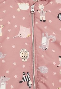 Roze stof met een zilveren rits, bedrukt met lachende cartoon dieren waaronder een leeuw, olifant, zebra, krokodil en sterren.