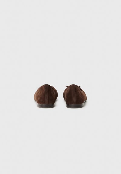 Mocassins en suede marron avec un petit talon, présentant une finition lisse et un design minimaliste. Des lacets accentuent l'avant, offrant un look classique.