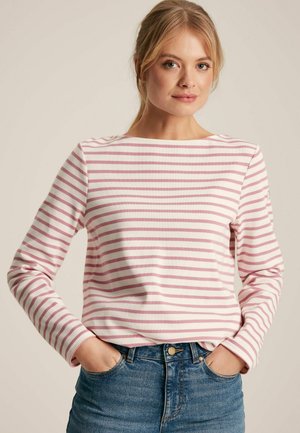 Striped long-sleeve shirt in white with pink horizontal stripes, featuring a scoop neckline and a relaxed fit. Styled with blue denim jeans.