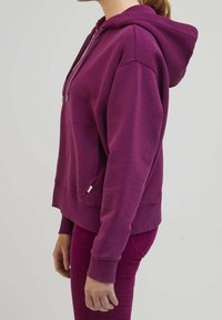 Lila bomullshuvtröja med ficka fram, ribbade ärmslut och justerbar dragsko i huvan, buren med matchande byxor.