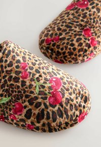 Leopard-print slippers with red cherry accents, made of soft fabric, featuring a rounded shape and plush texture for comfort.