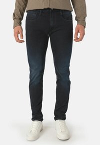 Mörk tvättade denimjeans med slim fit, med framfickor och subtila blekningsdetaljer. Bärs med vita sneakers.