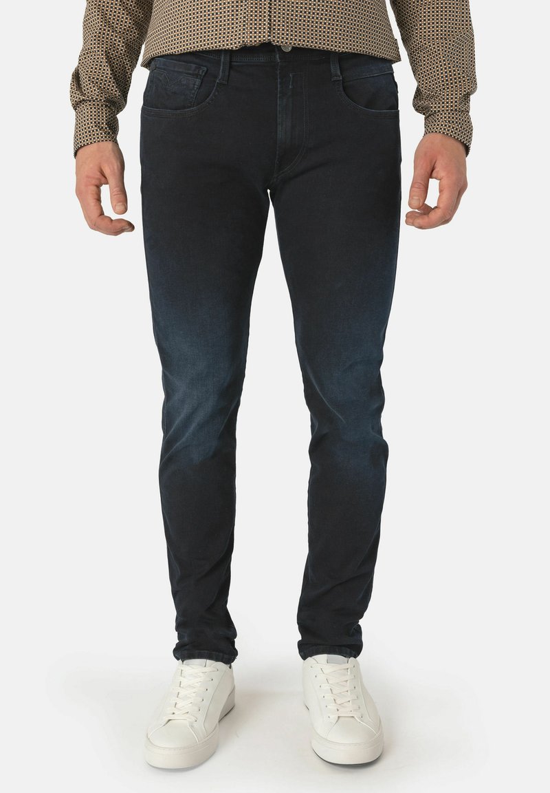 Mörk tvättade denimjeans med slim fit, med framfickor och subtila blekningsdetaljer. Bärs med vita sneakers.