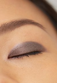 Fard à paupières dans des nuances grises scintillantes sur une paupière fermée. Texture lisse, bords estompés, et cils bien définis améliorent le look. Subtil éclat métallique.