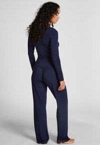 Ensemble de loungewear navy comprenant des manches longues et un pantalon avec des accents en dentelle à l'ourlet. Fabriqué en tissu doux et extensible pour un confort optimal.