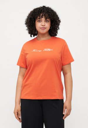 Camiseta de algodón naranja con mangas cortas y cuello redondo, con el logo de "Tommy Hilfiger" en escritura blanca en la parte frontal.