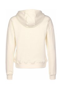 Krémová mikina s kapucí a volným střihem. Obsahuje žebrované manžety a lem, měkkou texturu a švy s detailem prošití.