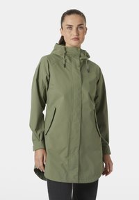 Αδιάβροχο μπουφάν σε ελαιώδες πράσινο με κουκούλα, που διαθέτει φερμουάρ και κούμπωμα με πατιλέτα, δύο πλαϊνές τσέπες και ελαφρώς μακρύτερη πλάτη για επιπλέον κάλυψη.