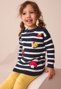 Knit sweater with navy and white stripes, featuring colorful fruit and flower appliqués. Paired with yellow leggings with star accents.