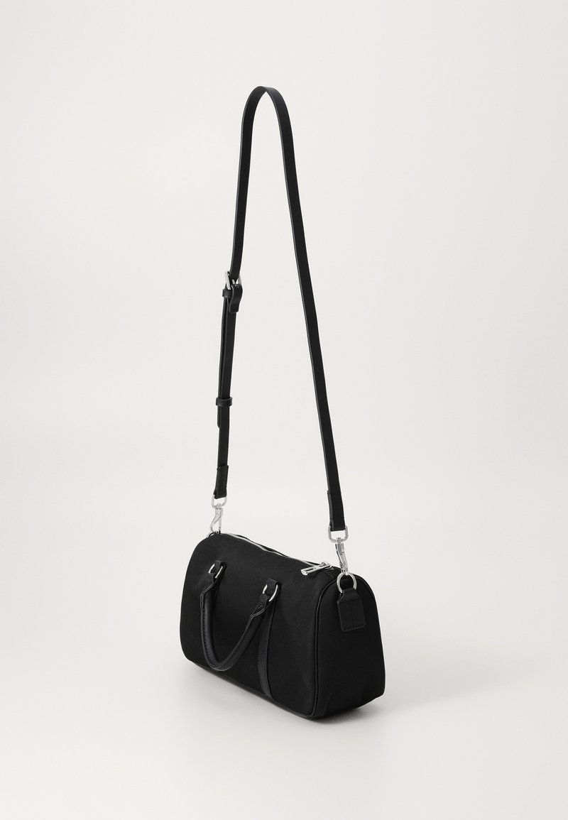 Borsa da viaggio nera in tela con accessori in metallo argento, manici superiori doppi, tracolla regolabile e chiusura a zip. Texture liscia e forma arrotondata.