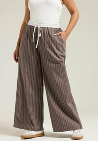 Bruna randiga vida byxor med elastisk midja och vit dragsko, med sidfickor och en lätt tygstruktur.