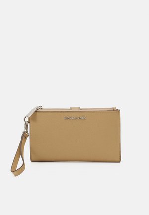 Portefeuille bracelet en cuir marron clair avec fermeture éclair argentée, sangle amovible et logo Michael Kors à l'avant.