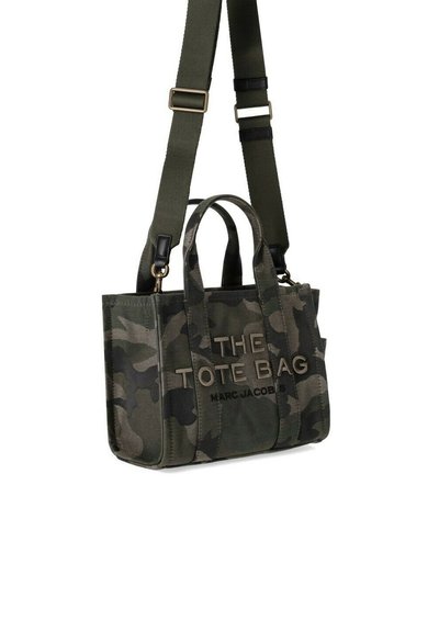 Kamuflāžas auduma soma ar diviem augšējiem rokturiem, regulējamu plecu siksnu un embossētu tekstu, kas lasāms "THE TOTE BAG MARC JACOBS."