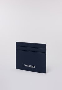 Portafoglio in pelle Trussardi blu navy con due slot per carte e nome del marchio in rilievo su uno sfondo chiaro semplice.