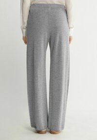 Grå vida byxor i mjukt tyg med en slät textur och elastisk midja, som slutar strax ovanför ankeln.