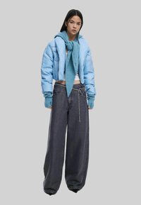 Heledad sinise värvi lühike puffjakker, sobiv kudumiskootud sall, valge pluus ja tumedad laiade jalgadega teksad, millel on kett ja südame aktsent.