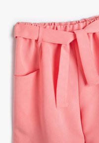 Pantalones de tiro alto rosa, con un acabado texturizado y suave; cuentan con un cinturón, bolsillo lateral y una cinturilla elástica fruncida.