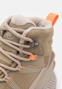 Beige høyhælte sneakers med pelskledning, teksturert materiale, oransje detaljer og grå snørebånd. Har sikkert snøresystem og merkevaredetalj.