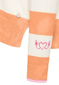 Gestreepte trui in oranje en wit; heeft een hartontwerp met vleugels in het roze en een metalen knoopdetail. Zachte textuur, geribbelde mouwen.