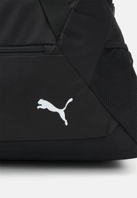 Zwarte rugzak met een gestructureerde afwerking, voorzien van een wit Puma-logo. Bevat een mesh accent en een ritszak aan de zijkant.