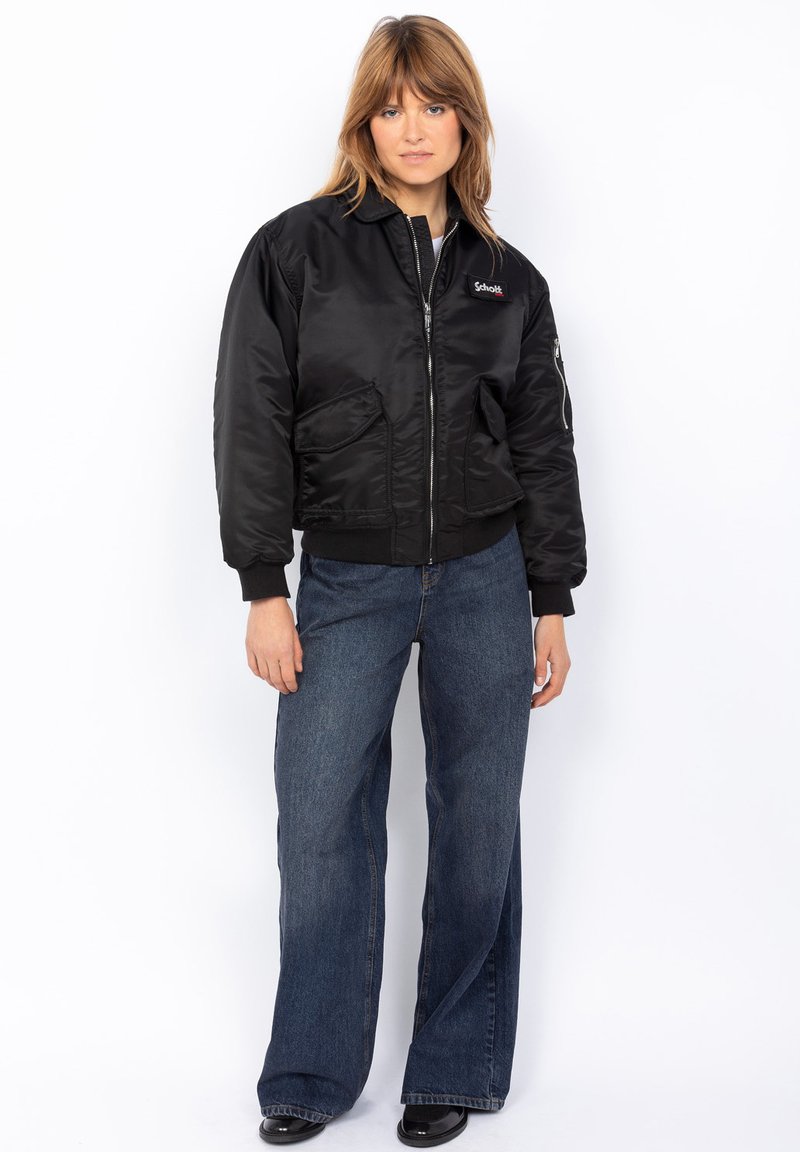 Must must jacket, millel ukse ees, küljetaskudega ja soonikkoes varrukatega. Materjal on sile ja läikiv, rinnal on logotäht.