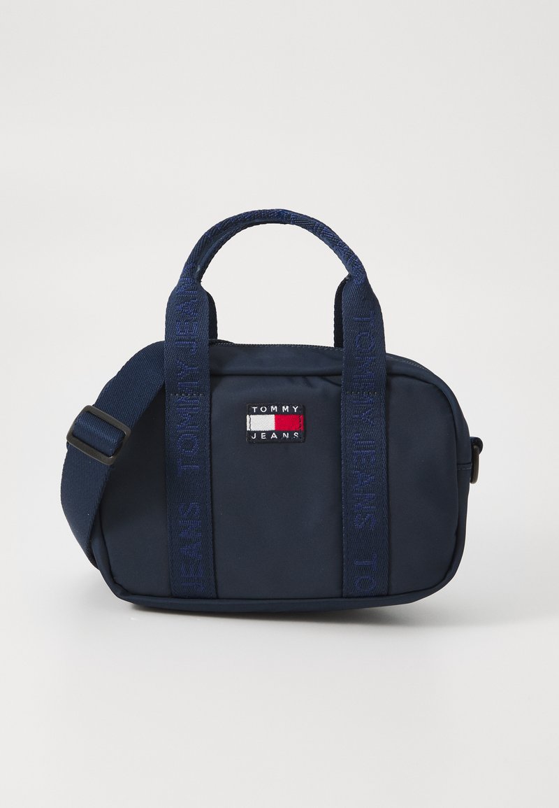Sac Tommy Jeans bleu marine de forme rectangulaire, en tissu durable, avec deux poignées supérieures, une sangle ajustable et un détail de logo brodé.