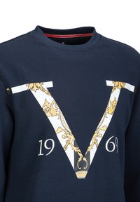 Navy Sweatshirt mit einem großen weißen und goldenen "V"-Design, das komplizierte goldene Details aufweist und darunter "1969" gedruckt ist. Aus Baumwollmaterial.