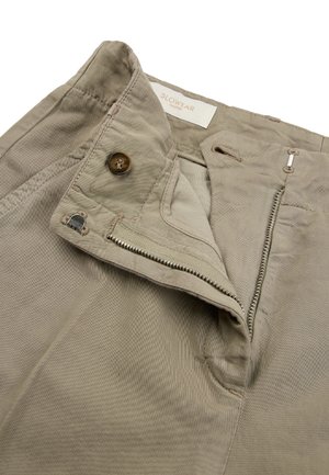Beige broekband die een gedeeltelijk open ritssluiting, knoopsluiting en merklabel "Slowear Incotex" aan de binnenkant toont.