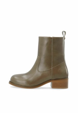 Bottine en cuir vert olive avec un petit talon bloc en bois et un onglet à l'arrière, présentée en profil latéral sur fond blanc.