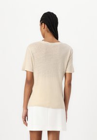 Beige rövid ujjú felső, puha, texturált felülettel. Kerek nyakkivágású és enyhén laza szabású, fehér szoknyával párosítva.
