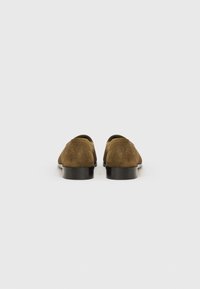 Καφέ καστόρινες παπούτσια με υφή και στρογγυλεμένη μύτη, με μαύρη, χαμηλή σόλα και μινιμαλιστικό σχέδιο.