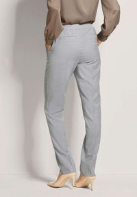 Lichtgrijze op maat gemaakte broeken met een soepele textuur, voorzien van zijzakken en een licht toelopende pasvorm, gecombineerd met huidskleurige hoge hakken.