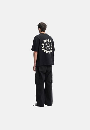 Black oversized t-shirt with graphic "DUST" on the back, paired with black cargo pants featuring multiple pockets and a relaxed fit.