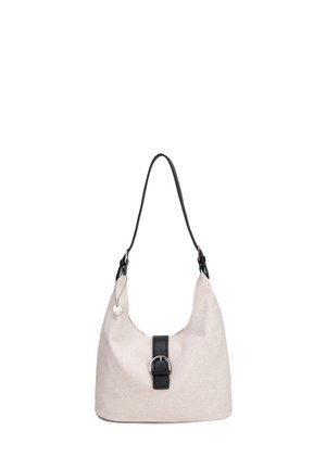 Beigefarbene Stoff-Schultertasche mit schwarzem Schnallenriemen, einem schwarzen Griff und rundem silbernem Anhänger an der Seite.