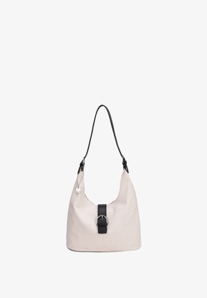 Beigefarbene Stoff-Schultertasche mit schwarzem Schnallenriemen, einem schwarzen Griff und rundem silbernem Anhänger an der Seite.