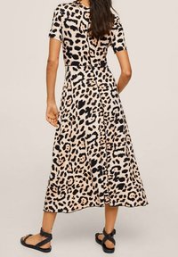 Robe imprimée léopard avec un corps ajusté, des manches courtes et une longueur midi évasée. Fabriquée en un matériau lisse avec une fente sur le côté.