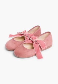 Ballerines en daim rose avec un bout arrondi et de grands nœuds en velours à l'avant. Semelle plate en caoutchouc avec un intérieur doux.