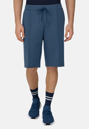 Marineblaue Sportshorts mit Kordelzugbund, Seitentaschen und glatter Textur, getragen mit gestreiften marineblauen Socken und sportlichen Schuhen.