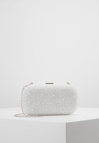 Bolso de mano blanco cubierto de adornos con aspecto de perlas, con forma rectangular, cierre de metal y cadena de plata desmontable.