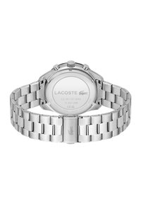 Montre en acier inoxydable avec un bracelet à maillons et un boîtier rond argenté. Présente un dos lisse avec un logo gravé et une résistance à l'eau.