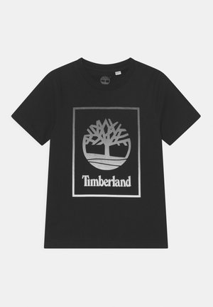 Czarna koszulka z krótkim rękawem z dużym srebrnym logo Timberland przedstawiającym drzewo wewnątrz kwadratu z przodu.