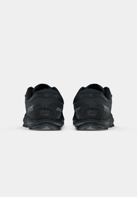Black running shoes with a textured fabric upper, rubber outsole, and reinforced heel. Features include 'Gaiter Trap' branding.