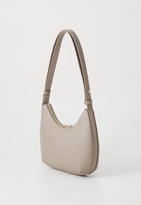 Sac à main en cuir beige avec une silhouette courbée, une fermeture zippée en haut et une sangle fine et ajustable. Présente une finition texturée.