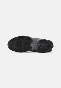 Black athletic shoe sole featuring textured rubber for traction, with distinct patterns and a molded footbed for support.