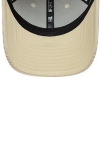 Beige keps med svart skärm, tillverkad av strukturerad tyg. Har en sydd skärm och inuti finns det taping som är märkt "9FORTY."