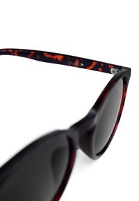 Sluneční brýle ve stylu kočičích očí s tmavými obroučkami, zdobené abstraktními vzory v oranžové a fialové barvě. Černé čočky a metalick�ý akcent na spánku.