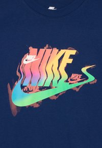 Námořnická modrá trička s vícebarevným logem Nike s přechody růžové, oranžové, zelené a modré; kulatý výstřih a bavlněná tkanina.