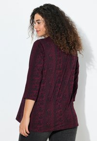 Haut à motif bourgogne avec des manches trois-quarts, coupe décontractée et tissu texturé. Design floral remarquable et ourlet légèrement arrondi.