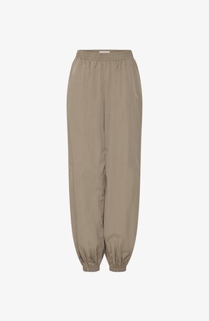 Laahtised beežid püksid, millel on elastne vöökoht ja koondatud elastsed sääreotsad, esitletud ühevärvilise valge tausta ees.